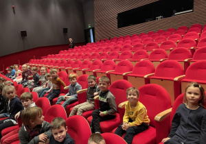 dzieci siedzą w sali teatralnej